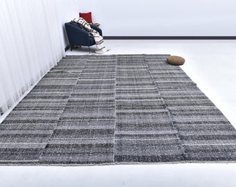 May include: A black and white striped rug with a woven texture. The rug is laid out on a white floor.