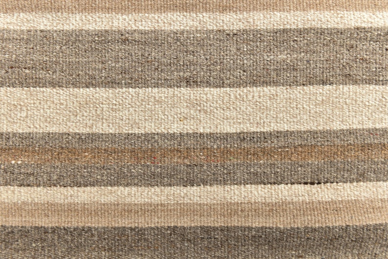 May include: A close-up of a woven fabric with horizontal stripes in shades of brown, beige, and white.