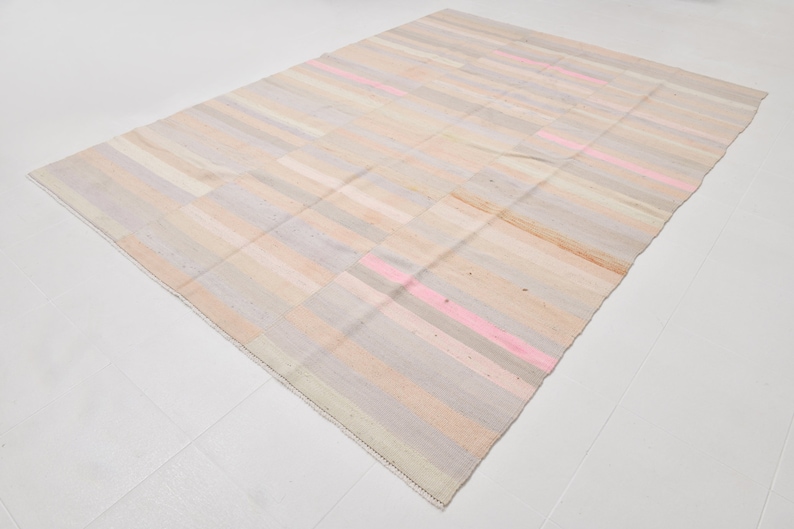 K&ouml;nnte beinhalten: Ein handgewebter Teppich mit einem gestreiften Muster in Beige-, Rosa- und Graut&ouml;nen. Der Teppich hat einen abgenutzten, Vintage-Look.