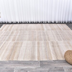 Pu&ograve; includere: Un tappeto beige chiaro con un sottile motivo a righe. Il tappeto ha una trama tessuta ed &egrave; realizzato in fibre naturali.