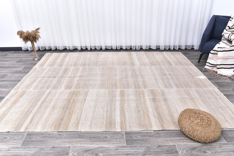 Pu&ograve; includere: Un tappeto beige chiaro con un sottile motivo a righe. Il tappeto ha una trama tessuta ed &egrave; realizzato in fibre naturali.