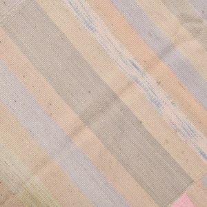 K&ouml;nnte beinhalten: Ein gewebter Teppich mit einem diagonalen Muster aus hellrosa, hellblauen und beigen Streifen.