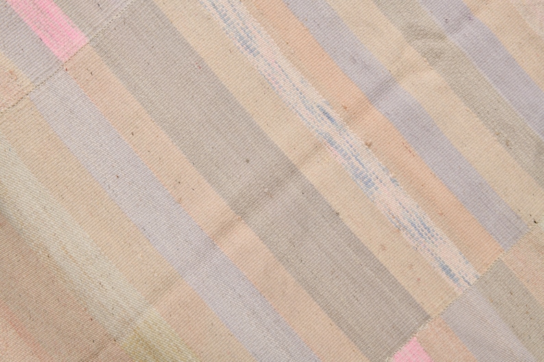 K&ouml;nnte beinhalten: Ein gewebter Teppich mit einem diagonalen Muster aus hellrosa, hellblauen und beigen Streifen.