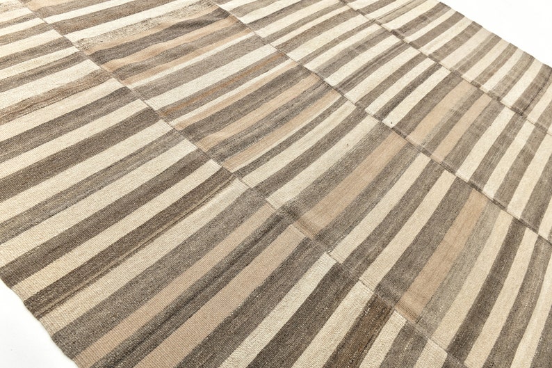 May include: A striped rug with a patchwork design in shades of brown and beige.