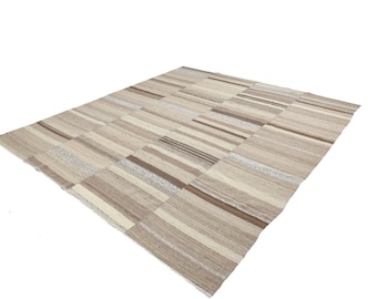 May include: A beige and brown striped area rug with a patchwork design. The rug is made of natural fibers and has a soft, textured feel.