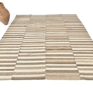 May include: A striped rug with a beige and brown colour scheme. The rug is made of wool and has a hand-woven texture.
