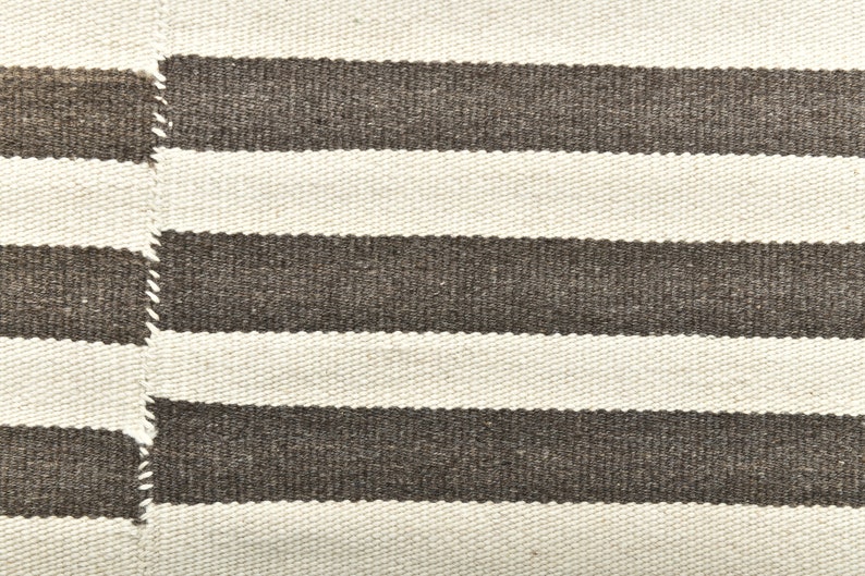 May include: A white and brown striped woven rug with a textured surface.