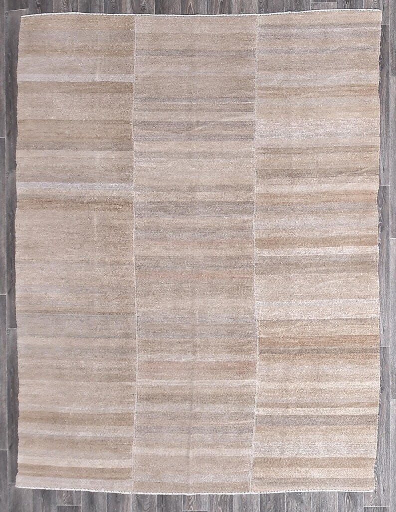Pu&ograve; includere: Un tappeto beige rettangolare con un sottile motivo a righe. Il tappeto &egrave; realizzato in un materiale morbido e tessuto.