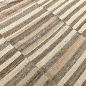 May include: A striped rug with alternating bands of beige and brown. The rug is made of woven fabric and has a subtle texture.