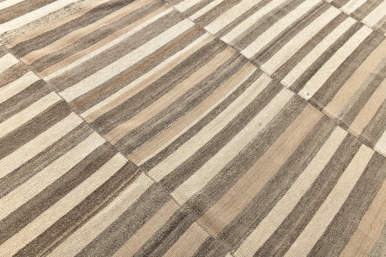 May include: A striped rug with alternating bands of beige and brown. The rug is made of woven fabric and has a subtle texture.