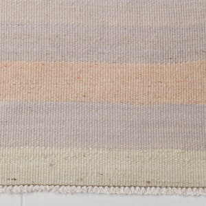 K&ouml;nnte beinhalten: Ein gewebter Teppich mit einem Streifenmuster in Beige-, Hellrosa- und Graut&ouml;nen. Der Teppich hat einen Fransenrand.