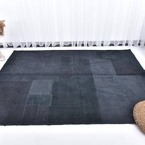 May include: A dark blue patchwork rug with a woven texture. The rug is made of different shades of blue fabric and has a rectangular shape.