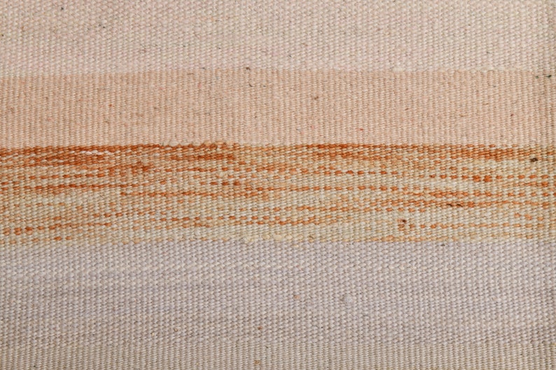K&ouml;nnte beinhalten: Nahaufnahme eines gewebten Stoffes mit drei horizontalen Streifen in den Farben Beige, Hellbraun und Dunkelbraun. Der Stoff hat eine strukturierte, handgewebte Optik.