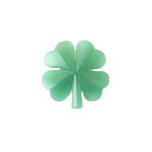 May include: A light green, four-leaf clover charm. The clover has a faceted design, with each leaf showing multiple planes. The stem is a solid, light green color. The background is plain white.