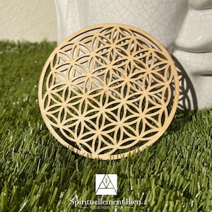 Peut inclure: Un dessous de verre rond en bois avec un motif de Fleur de Vie découpé au laser. Le dessous de verre est brun clair et a une finition en bois naturel.