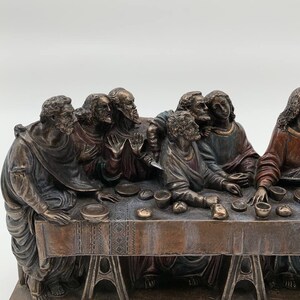 May include: A bronze sculpture depicting Leonardo da Vinci's The Last Supper. The sculpture features 13 figures seated around a table, with Jesus Christ in the center. The sculpture is detailed and realistic, with intricate facial expressions and clothing folds. The base of the sculpture is inscribed with "Last Supper By Leonardo."