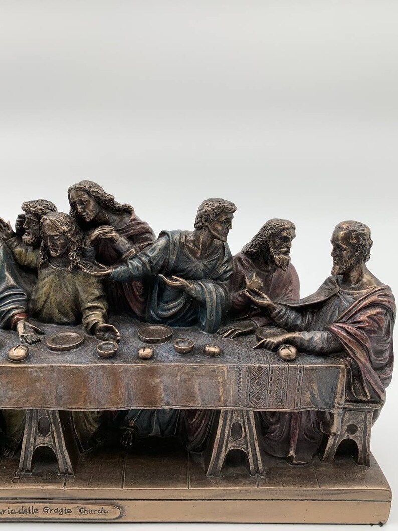 May include: A bronze sculpture depicting the Last Supper, featuring Jesus and his disciples seated around a table. The sculpture is detailed with realistic facial expressions and clothing. The base of the sculpture is inscribed with "Santa delle Grazie Church."