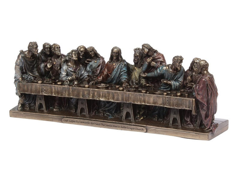 May include: A bronze sculpture depicting Leonardo da Vinci's The Last Supper, featuring 13 figures seated around a table. The sculpture is detailed with realistic features and painted in muted tones of brown, gold, and blue. The base of the sculpture is inscribed with "Last Supper by Leonardo da Vinci The Santa Maria delle Grazie Church."