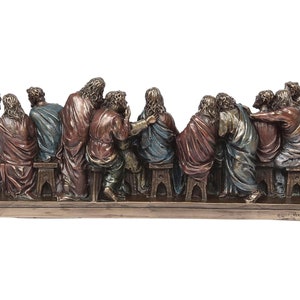 May include: A bronze sculpture depicting the Last Supper, featuring 13 figures seated around a table. The figures are detailed and realistic, with intricate clothing and facial expressions. The sculpture is mounted on a wooden base.