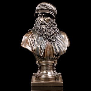 Könnte beinhalten: Bronzebüste eines Mannes mit Bart und Mütze. Die Büste steht auf einem quadratischen Sockel mit der Inschrift "LEONARDO DA VINCI 1452-1519" auf der Vorderseite.