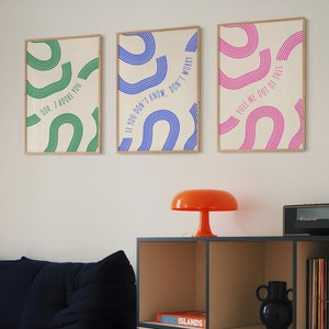 May include: Three framed prints with colorful abstract designs and text. The prints are hung on a white wall. The text on the prints reads "Ooh, I adore you", "If you don't know, don't worry", and "Pull me out of this".