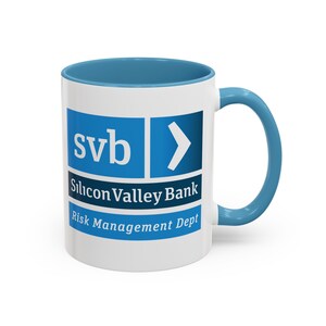 May include: White ceramic mug with a blue rim and handle. The mug has a logo that says "svb" and "Silicon Valley Bank" with the words "Risk Management Dept" below.