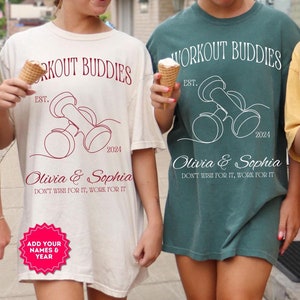 May include: Three people wearing white, green, and yellow t-shirts with the text "Workout Buddies" and a dumbbell graphic. The text "Est. 2024" and "Olivia & Sophia" are also on the shirts. The shirts have a distressed look.