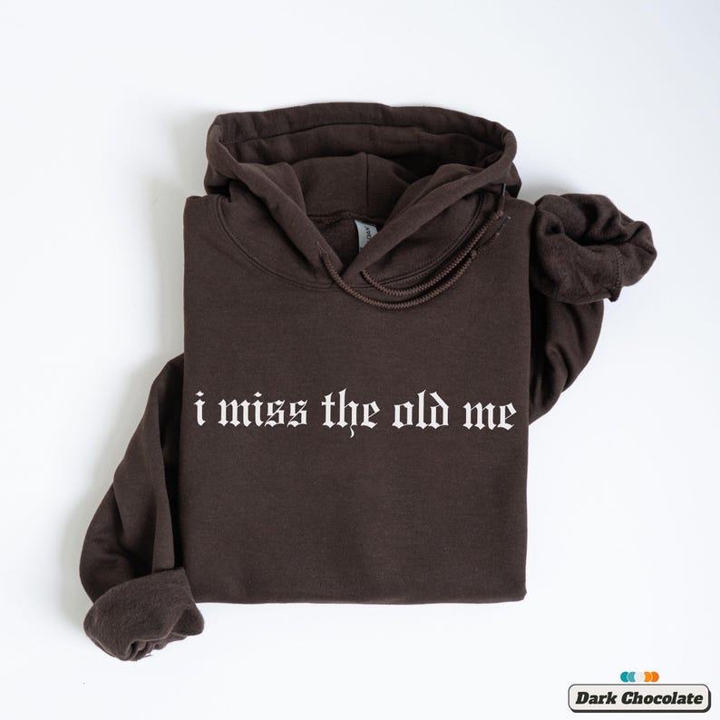 Puede incluir: Una sudadera con capucha marr&oacute;n oscuro con el texto "i miss the old me" impreso en blanco en la parte delantera.