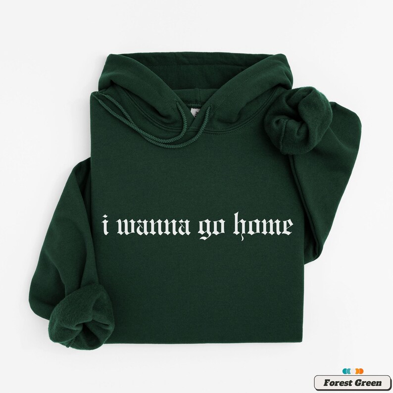May include: A forest green hooded sweatshirt with the text "i wanna go home" in white gothic lettering.