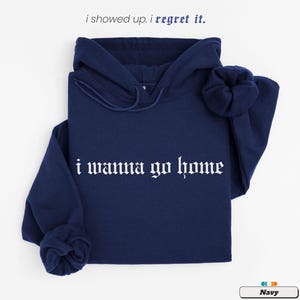 May include: A navy blue hoodie with the text "i wanna go home" in white gothic lettering.