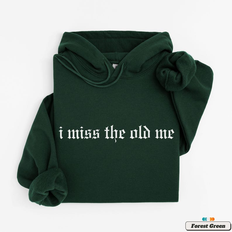 Puede incluir: Una sudadera con capucha de color verde bosque con el texto "i miss the old me" en fuente g&oacute;tica blanca.