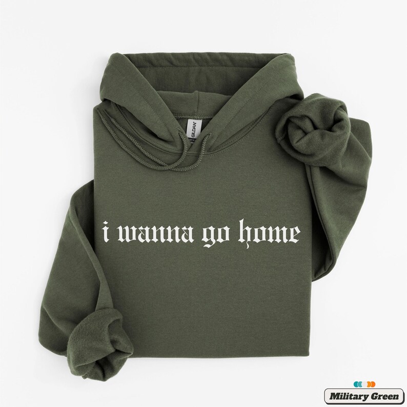 May include: A green hooded sweatshirt with the text "i wanna go home" in white gothic lettering.