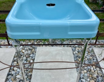 Lavabo vintage Crane Drexel: hierro fundido azul, patas cromadas, estilo retro de mediados de siglo.