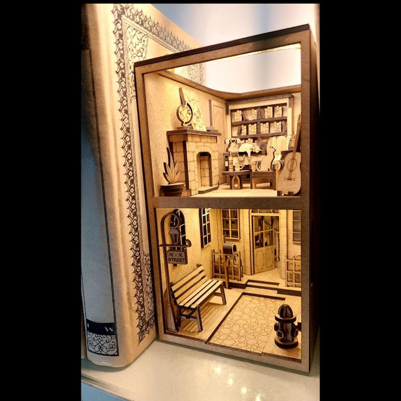 Peut inclure: Une maison miniature en bois avec un cadre en forme de livre. La maison a deux &eacute;tages, une chemin&eacute;e, un banc et une pancarte indiquant "Music Room".
