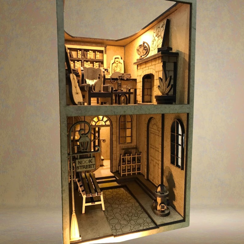 Peut inclure: Mod&egrave;le miniature en bois d'un b&acirc;timent de deux &eacute;tages avec une chemin&eacute;e, une biblioth&egrave;que et une enseigne indiquant "Nook Street". Le mod&egrave;le est &eacute;clair&eacute; de l'int&eacute;rieur, cr&eacute;ant une lueur chaleureuse.