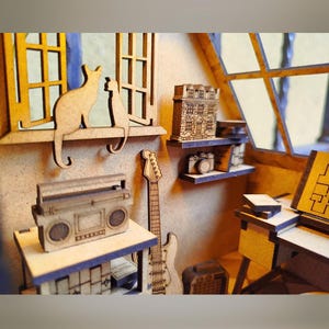May include: A wooden model of a room with a window, a cat, a guitar, a boombox, and a small house on a shelf. The room is decorated with a wooden floor and walls.