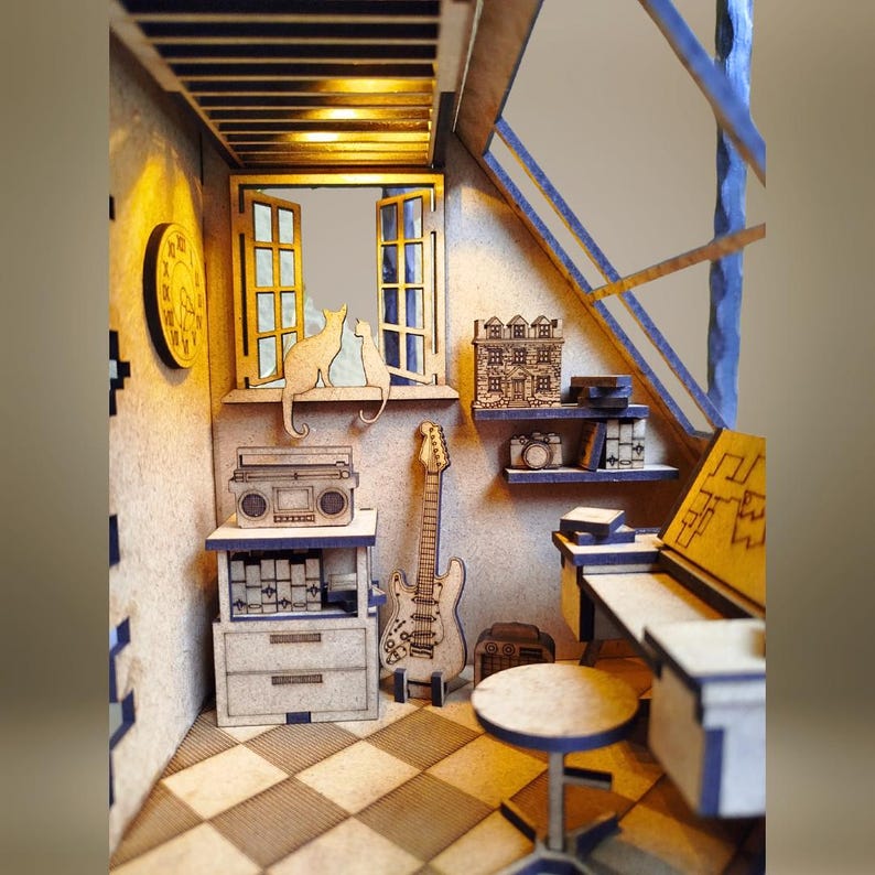 May include: A wooden model of a room with a window, a guitar, a radio, a shelf with books and a camera, and a desk with a chair. The room is decorated with a clock and two cats.