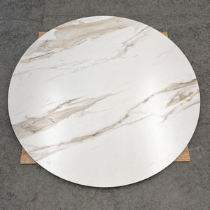 May include: Round white marble table top with brown veining. The table top is approximately 90 cm in diameter.