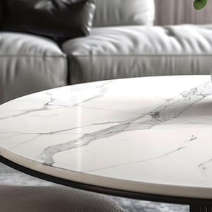 May include: A white round table with a black metal base. The table top has a marble pattern with grey veins.