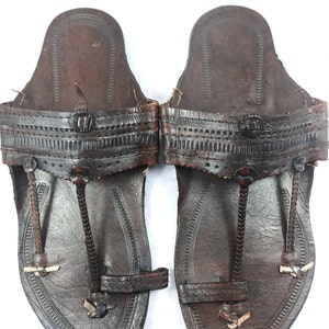 May include: A pair of brown leather sandals with intricate stitching and a pointed toe.