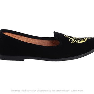 May include: Black velvet flat shoes with a gold embroidered design.