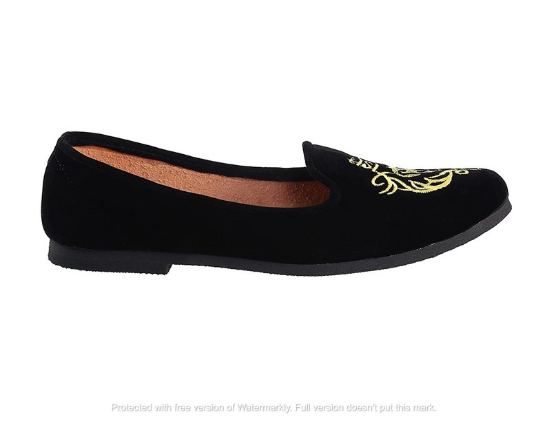 May include: Black velvet flat shoes with a gold embroidered design.