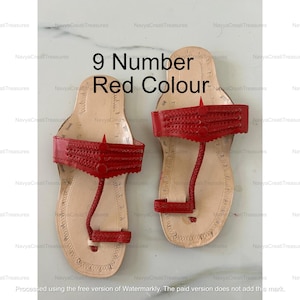 May include: A pair of red leather sandals with a toe loop and a strap across the top. The sandals are size 9. The sandals have a natural leather footbed and are displayed on a light background.