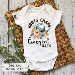 Könnte beinhalten: Weißer Baby-Strampler mit einem blauen Cowboyhut, floralen Akzenten und dem Text "Boots, Chaps, Cowgirl Hats".