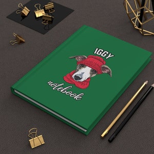 May include: Green notebook with a white dog wearing a red hat and scarf. The text on the notebook says "IGGY notebook".