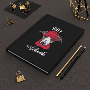May include: Black notebook with a white and red illustration of a dog wearing a red hat and scarf. The text "IGGY notebook" is printed on the cover.