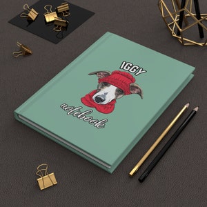 May include: A green notebook with the text "IGGY notebook" and a cartoon illustration of a dog wearing a red hat and scarf.