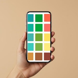 May include: A smartphone displays a colorful grid of squares in various shades of blue, green, orange, and yellow. The phone is held in a hand against a neutral background. The screen's design suggests a color palette or design tool.