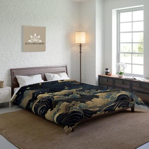 May include: A navy blue and gold comforter with a celestial design featuring clouds, waves, and stars. The bedding is on a wooden bed frame in a bedroom with a neutral color palette. The comforter has a unique, artistic pattern.