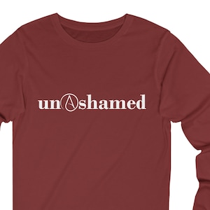 Puede incluir: Una camiseta de manga larga de color granate con el texto "unashamed" en letras blancas, que incluye un círculo con una 'A' en su interior.